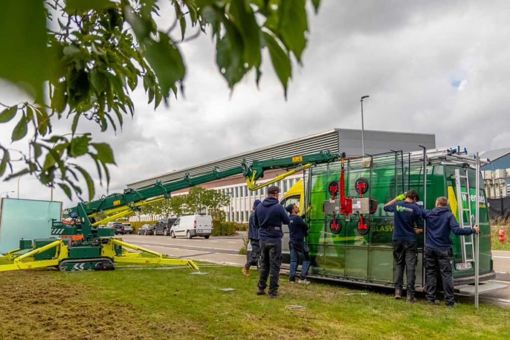 Nieuwe ruit wordt van de wagen gehaald met behulp van kraan
